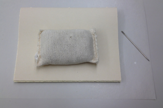 small weight presses down on the text block, or two book sections sewn together